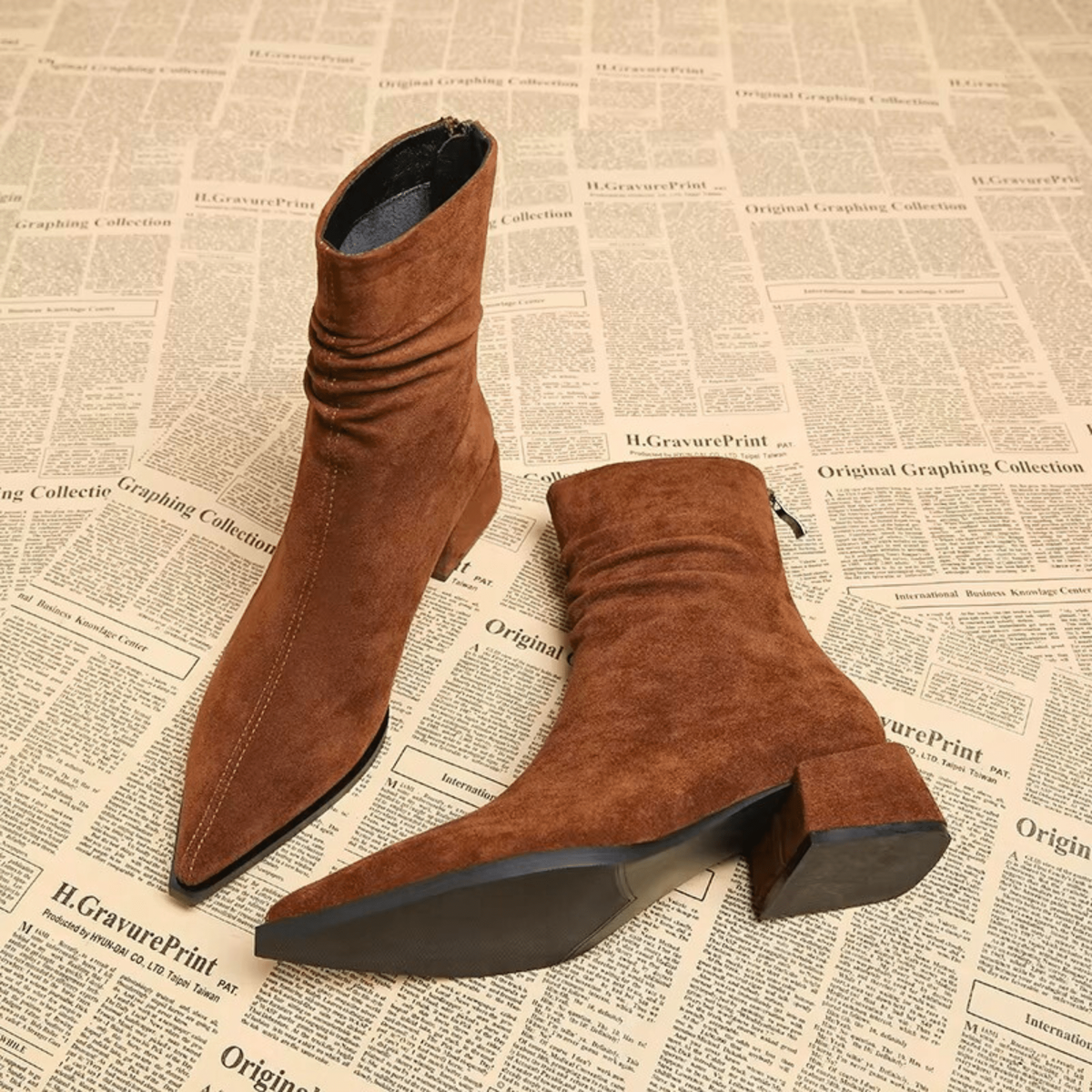 Brown ankle boots displayed from above and underneath, highlighting the pointed toes, block heels, and dark soles.