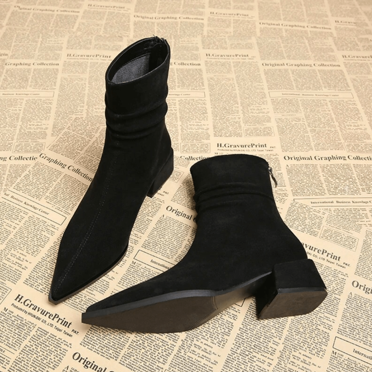 Black ankle boots displayed from above and underneath, highlighting the pointed toes, ruched shafts, and block heels.