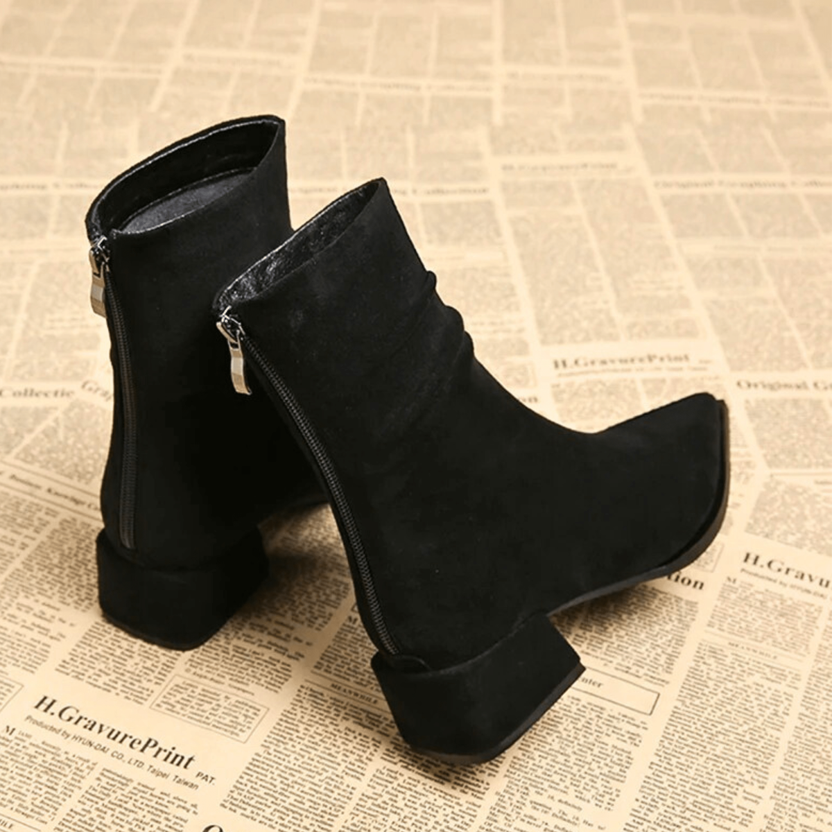 Black ankle boots shown from the back and side, revealing the full-length side zippers, ruched shafts, and block heels.