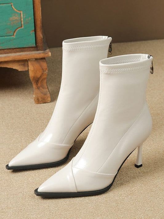 Black pointed-toe ankle boots with stiletto heel and back zipper closure modeled on feet._2