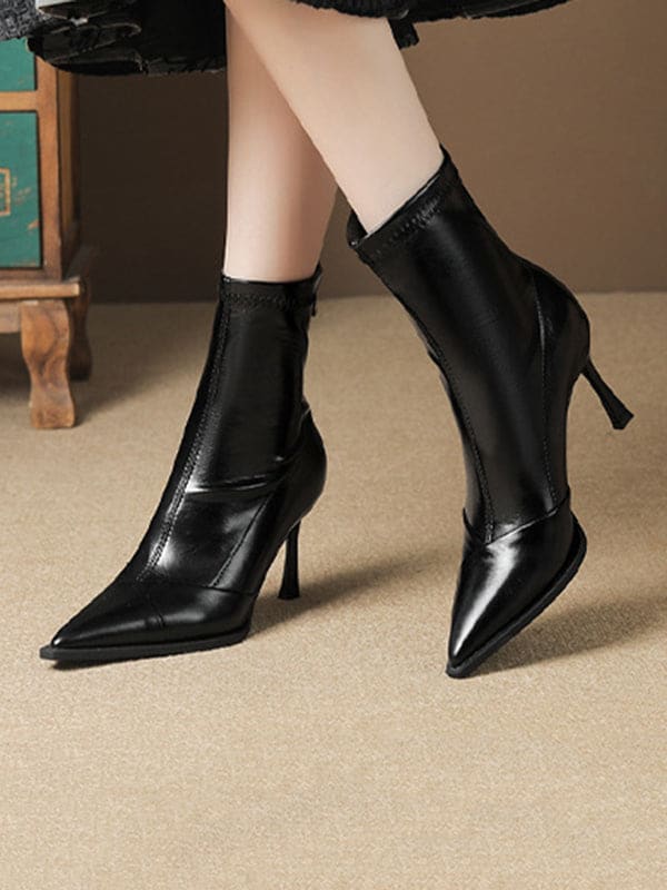 Black pointed-toe ankle boots with stiletto heel and back zipper closure modeled on feet._3