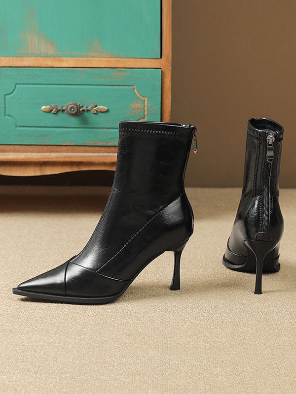 Black pointed-toe ankle boots with stiletto heel and back zipper closure modeled on feet._6