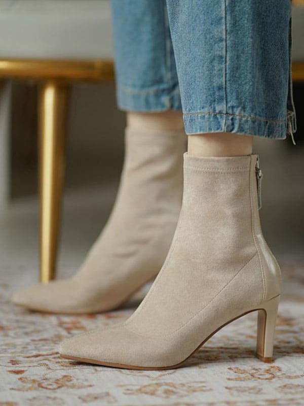 Woman wearing beige pointed toe sock boots with mid heel and back zipper, styled with cropped jeans._0