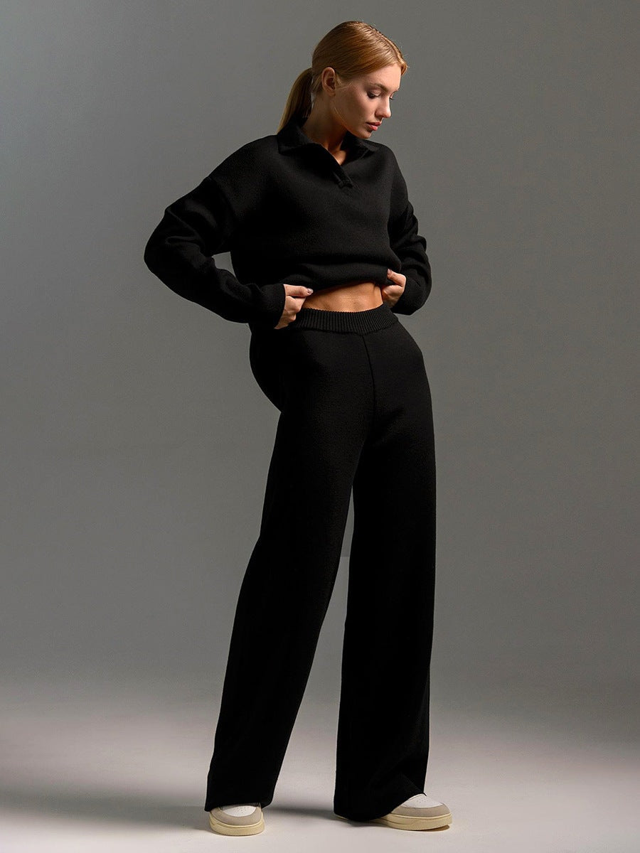 Model in the black set lifting the sweater slightly to reveal the elasticized waistband of the pants.