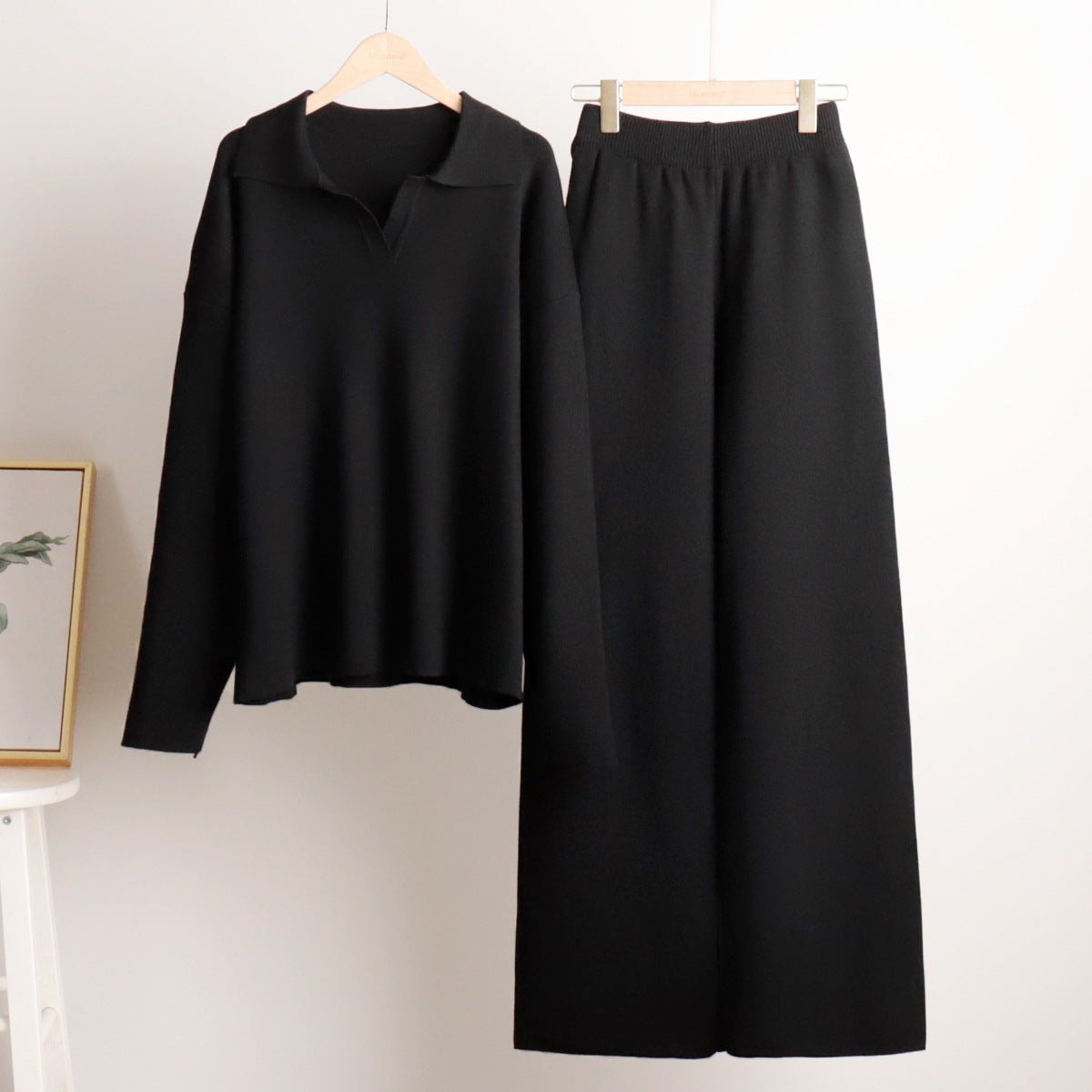 Black long-sleeve polo sweater and wide-leg pants displayed together on hangers.