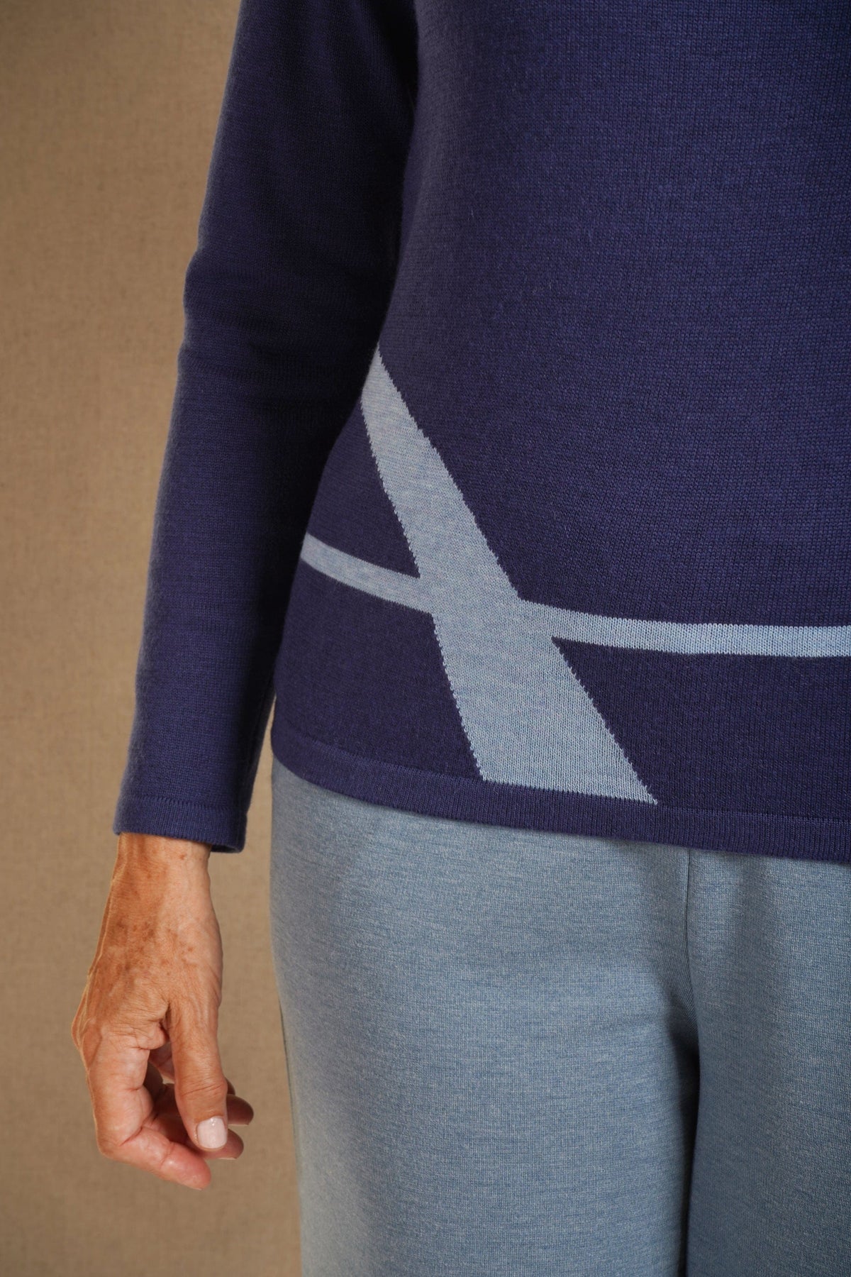 Woman wearing a long sleeve mock neck knit jumper with curved contrast panels across the front, worn with a long knit skirt outdoors._4