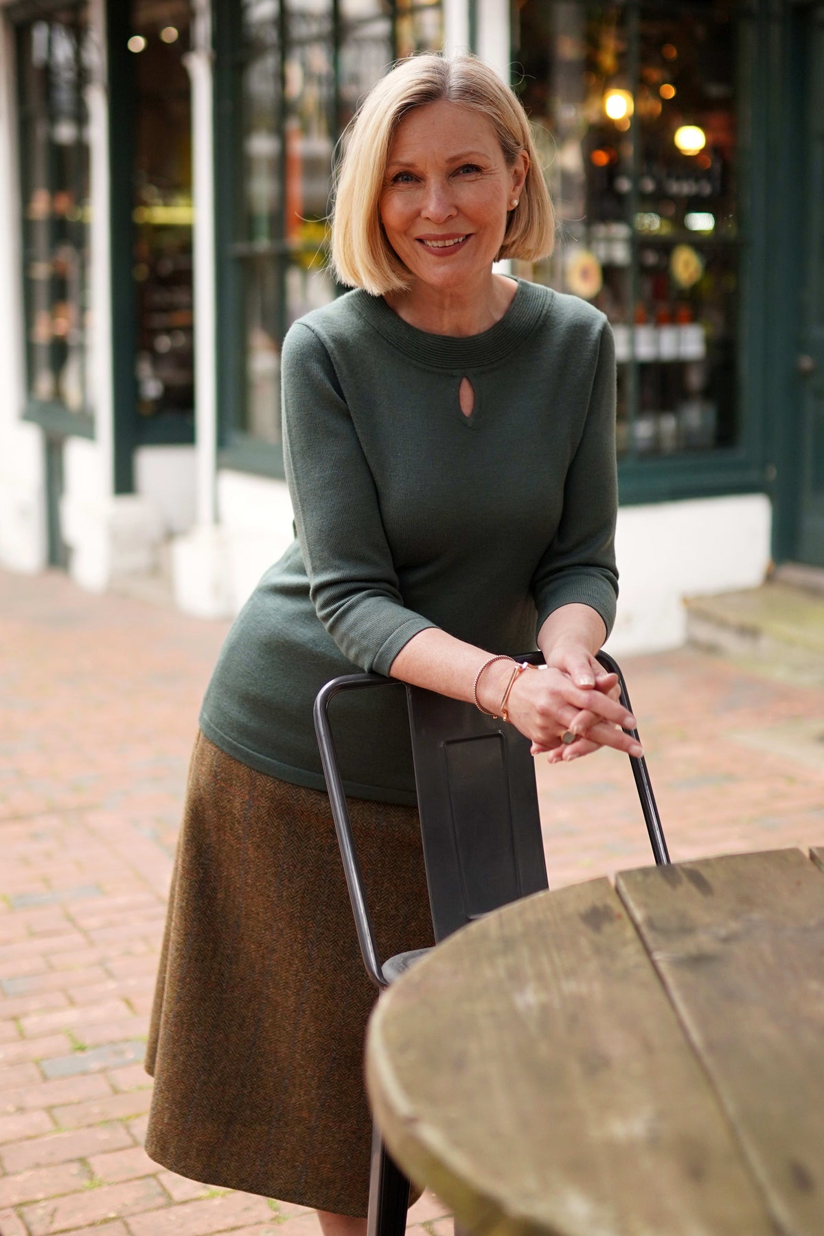 Woman wearing a fine knit long sleeve jumper with a ribbed round neckline and small keyhole opening at the centre front._2