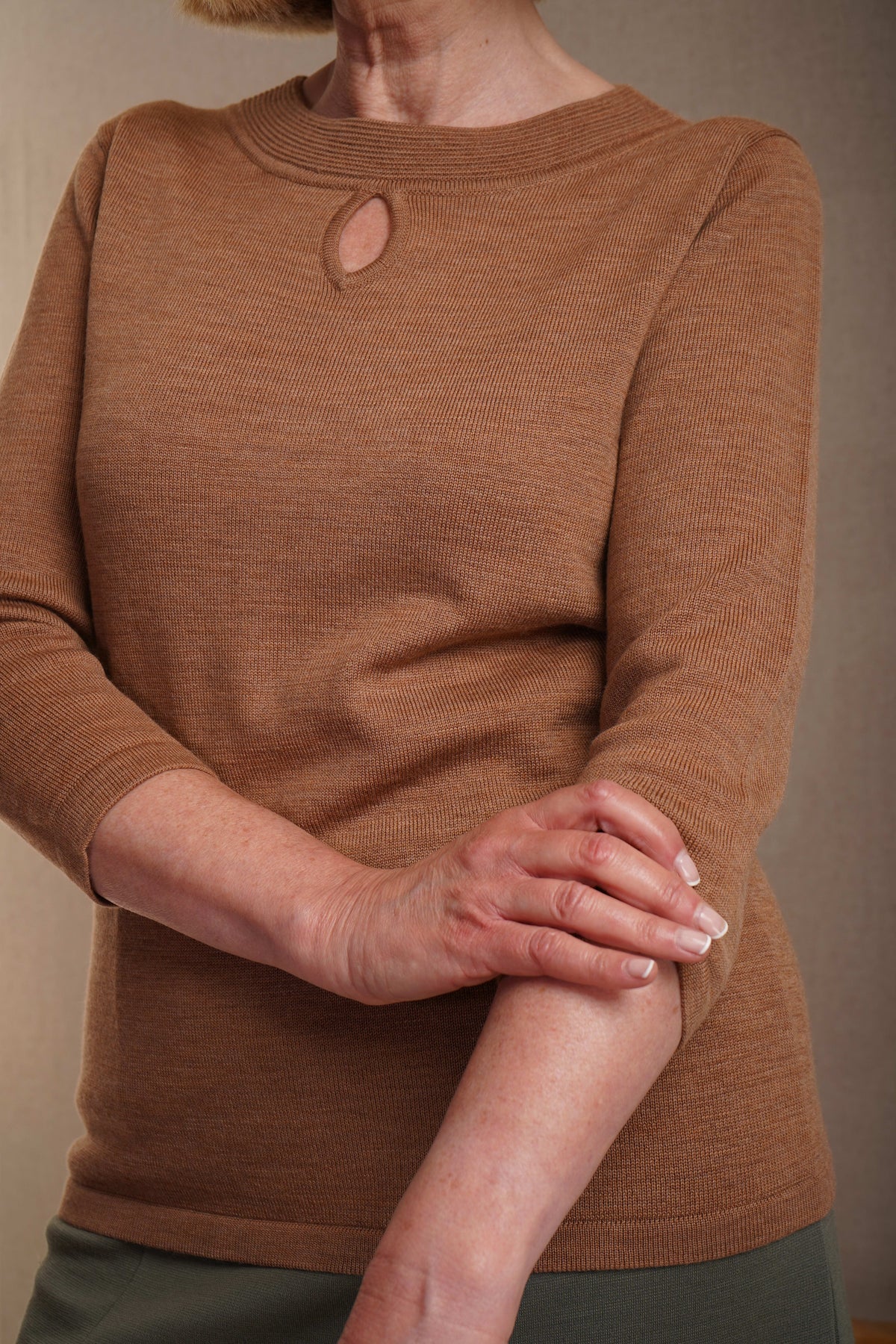 Woman wearing a fine knit long sleeve jumper with a ribbed round neckline and small keyhole opening at the centre front._8