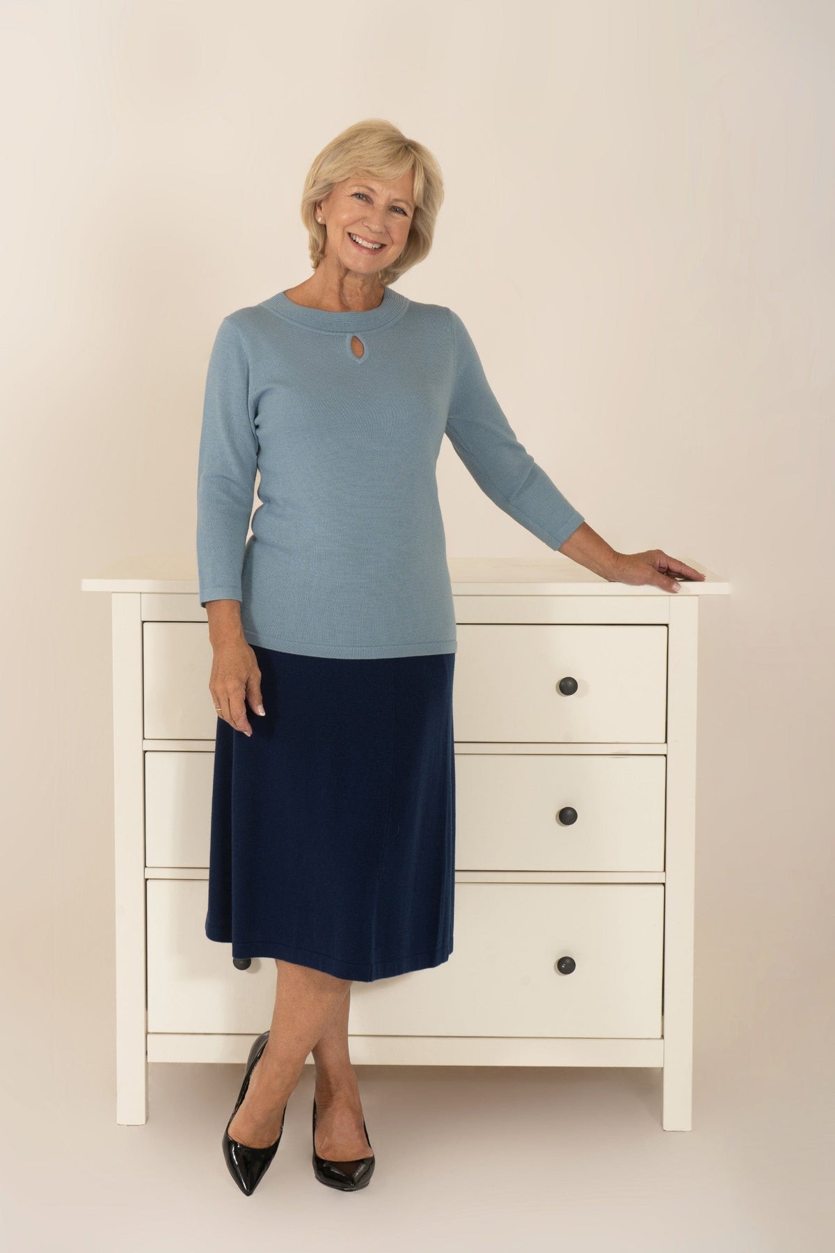 Woman wearing a fine knit long sleeve jumper with a ribbed round neckline and small keyhole opening at the centre front._9