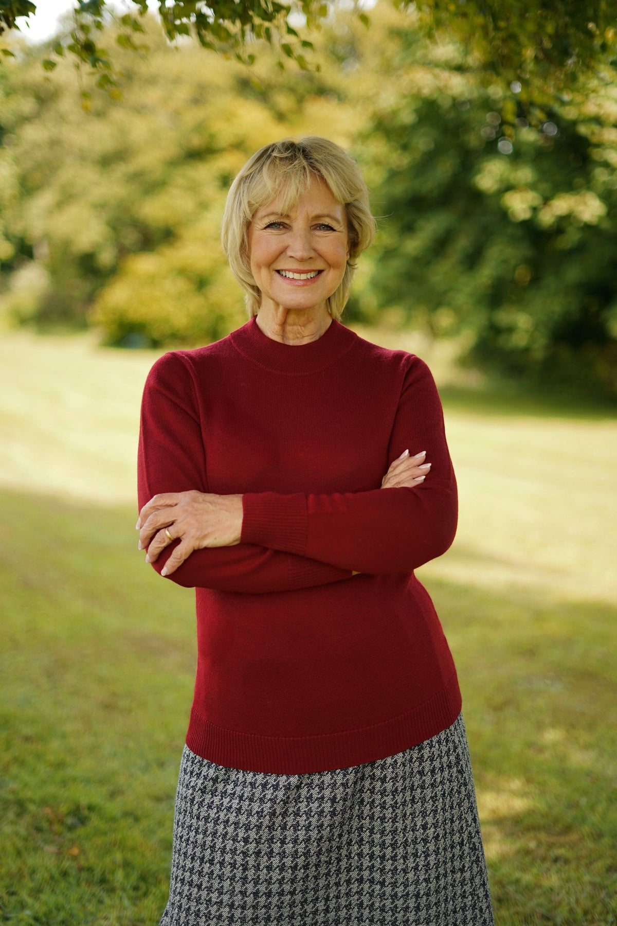 Woman standing outdoors wearing a long sleeve mock neck knitted jumper with ribbed cuffs and hem, paired with a houndstooth midi skirt._0