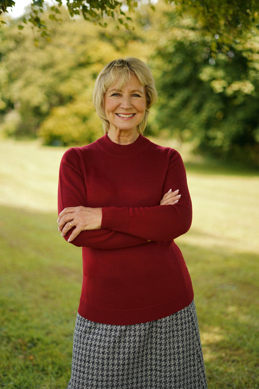 Woman standing outdoors wearing a long sleeve mock neck knitted jumper with ribbed cuffs and hem, paired with a houndstooth midi skirt._0