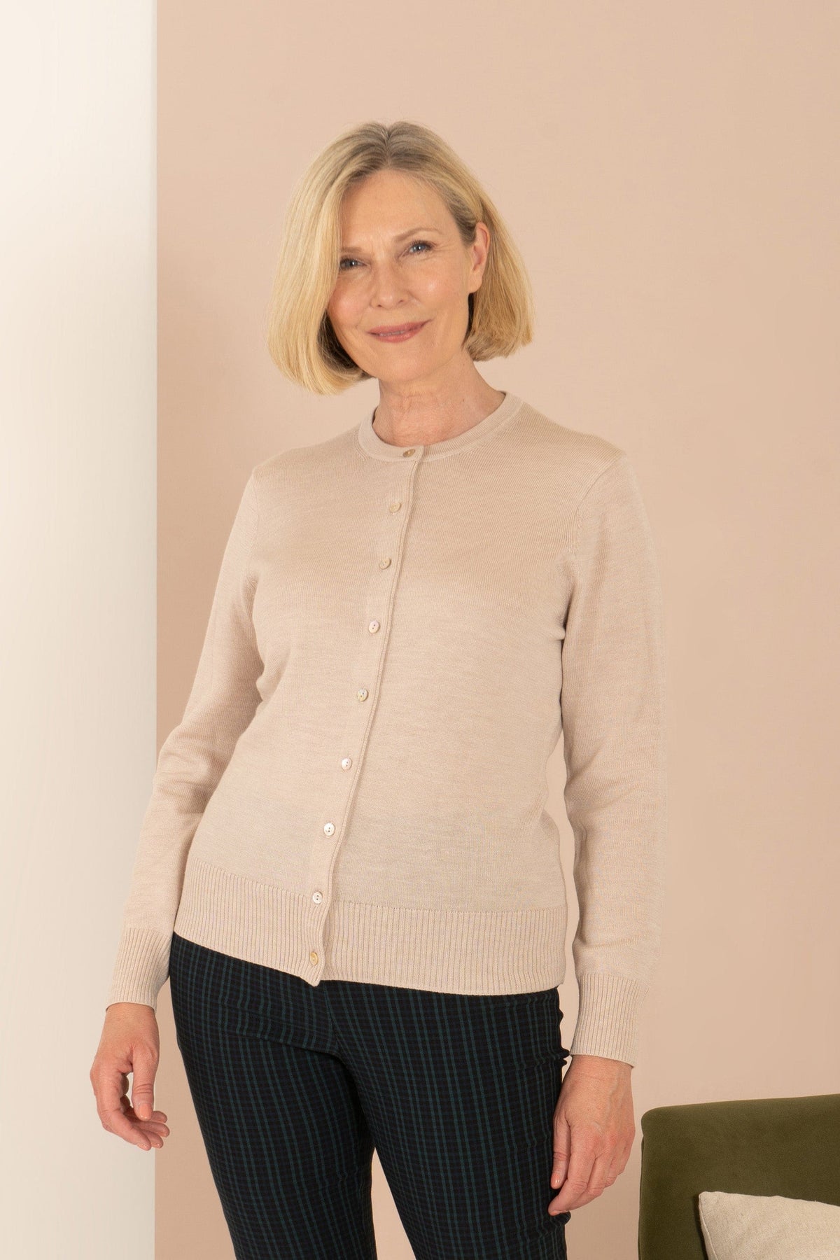 Woman wearing a long sleeve button front knit cardigan with a round neckline and ribbed cuffs and hem, with trousers._4