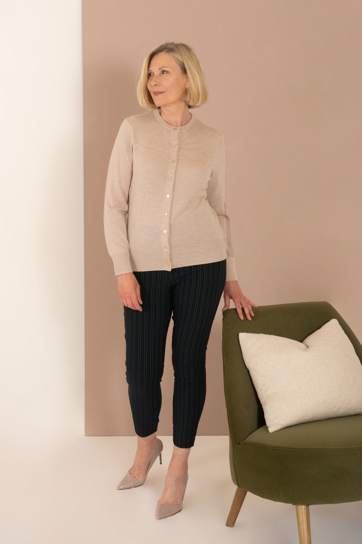 Woman wearing a long sleeve button front knit cardigan with a round neckline and ribbed cuffs and hem, with trousers._5