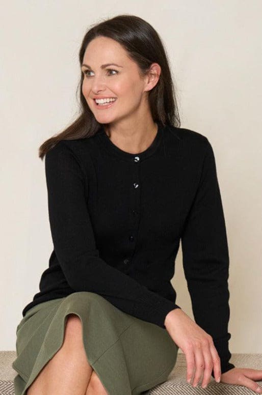 Woman wearing a long sleeve button front knit cardigan with a round neckline and ribbed cuffs and hem, with trousers._6