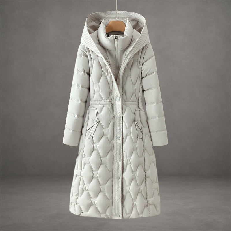 White quilted hooded longline coat featuring geometric quilting, a shaped waist, front closure, and angled flap pockets.
