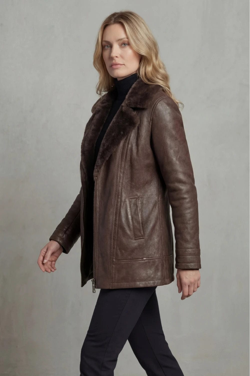 Woman viewed from behind wearing a hip-length zip-front jacket with a faux fur collar, welt pockets and ribbed sleeve detail._8