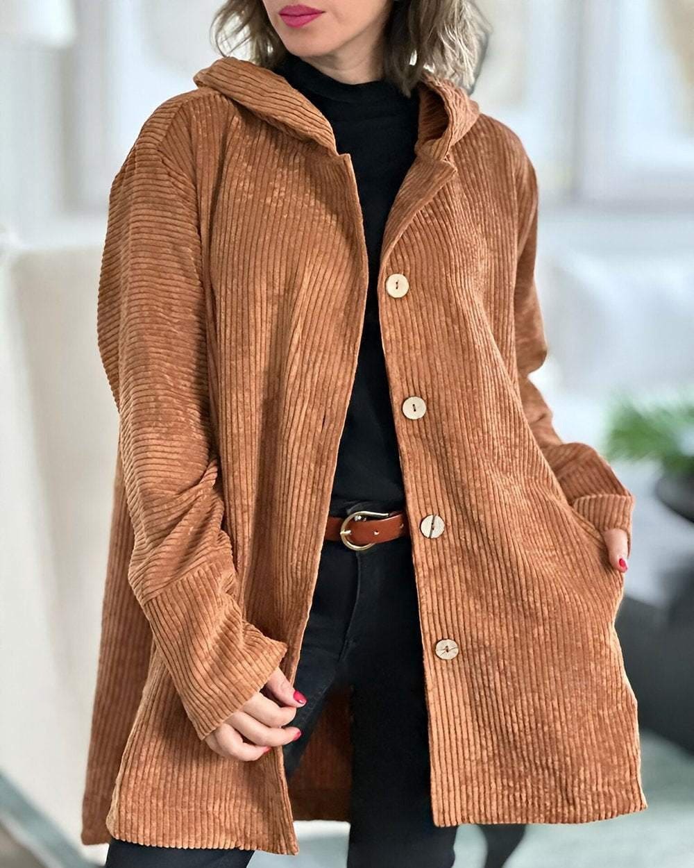 Woman wearing an open ribbed corduroy shirt jacket with four large buttons, point collar and patch pockets over a roll neck and jeans._0