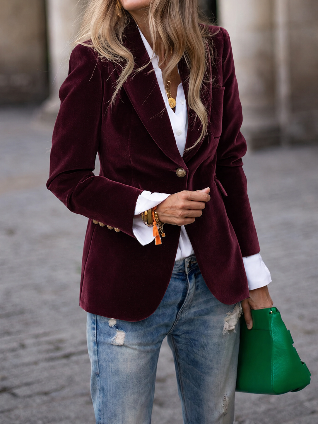 Burgundy single-button blazer with notched lapels, long sleeves, and decorative cuff buttons styled over a white shirt and distressed jeans.