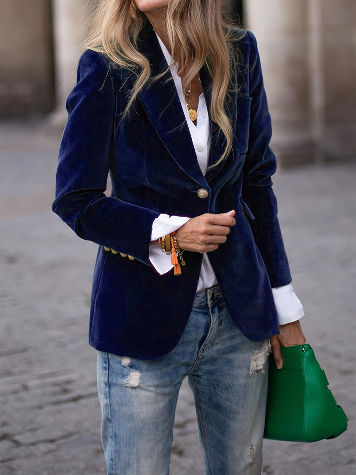 Deep blue tailored blazer featuring a single-button closure, notched lapels, and buttoned cuffs over a layered casual outfit.