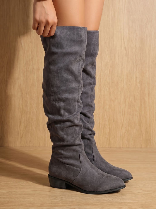 Gray slouchy over-the-knee boots with pointed toes and low block heels shown on a model.