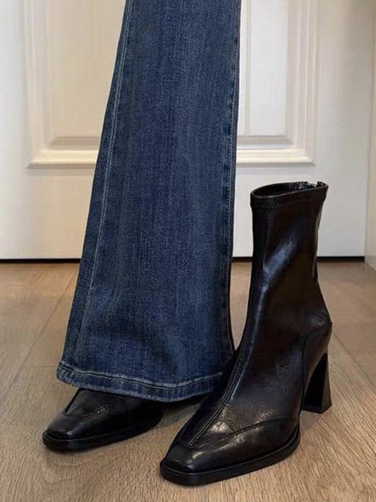 A pair of black ankle boots with a square toe and block heel worn with blue jeans._0