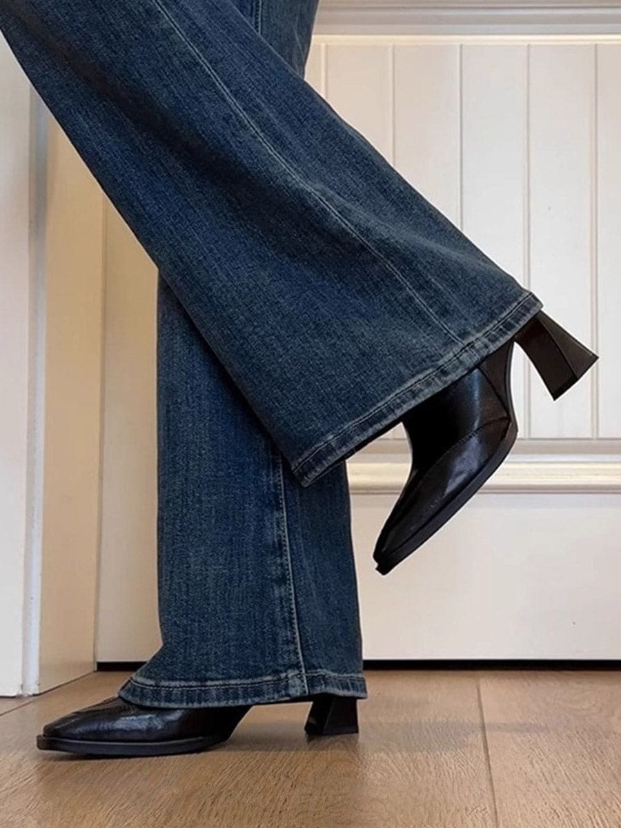 A pair of black ankle boots with a square toe and block heel worn with blue jeans._1
