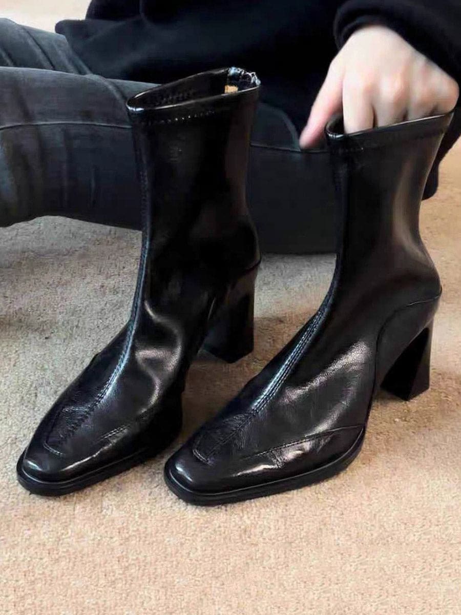 A pair of black ankle boots with a square toe and block heel worn with blue jeans._3
