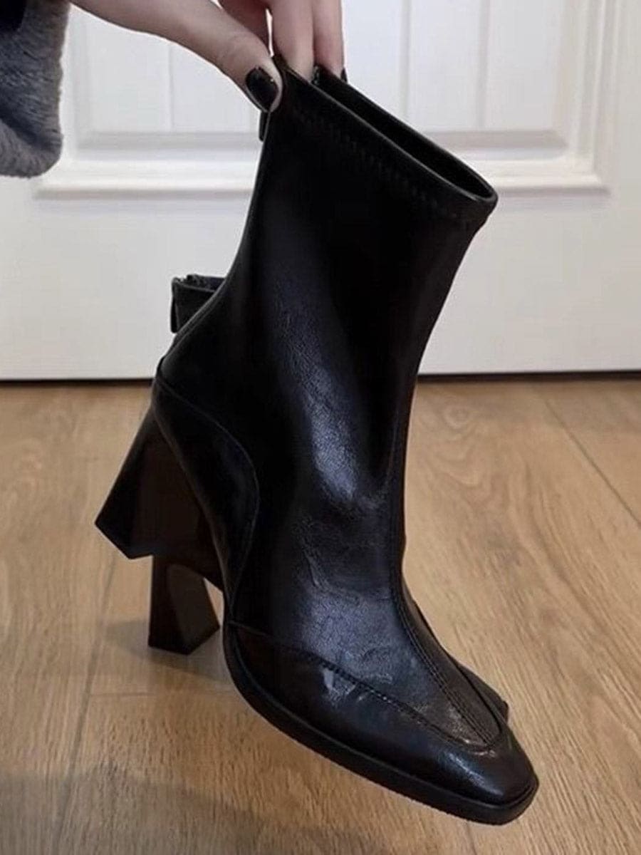A pair of black ankle boots with a square toe and block heel worn with blue jeans._4