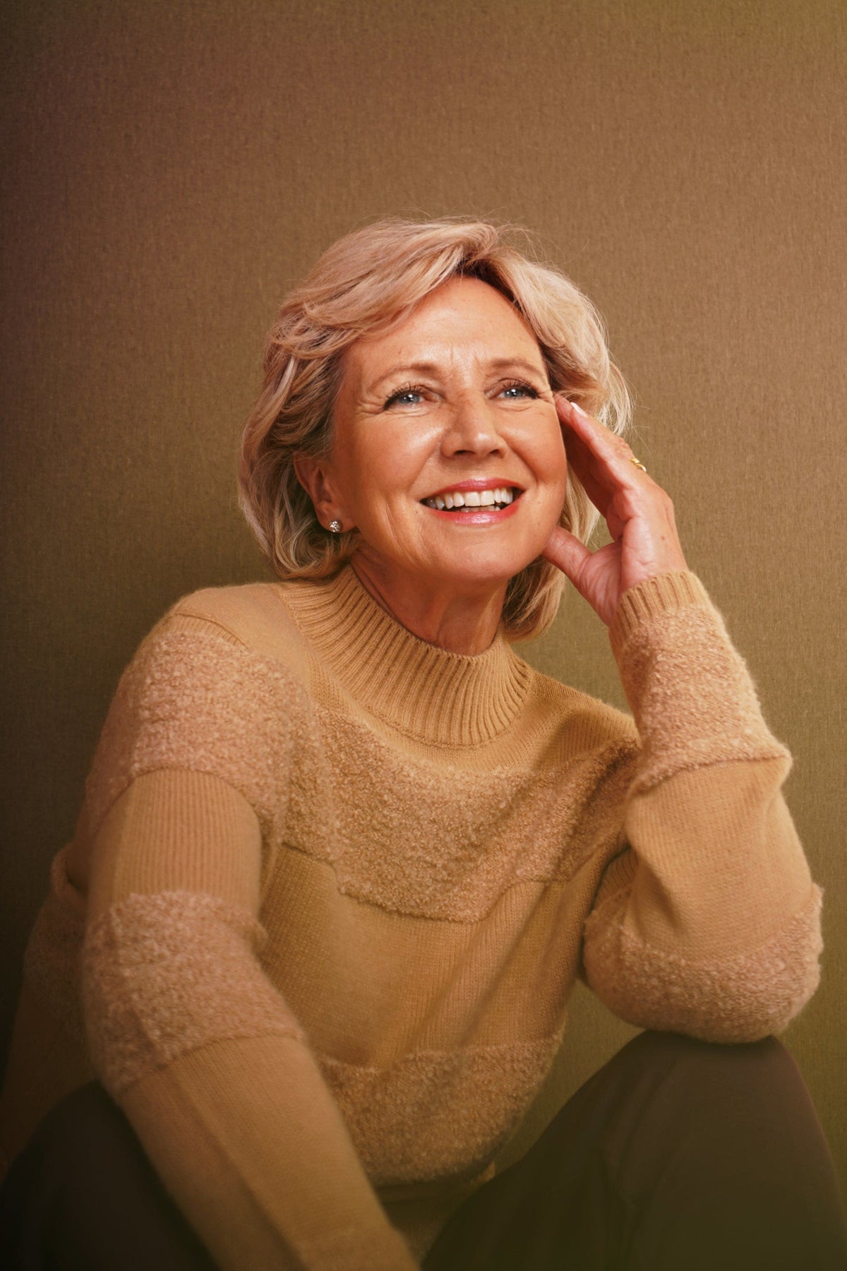 Woman sitting and smiling wearing a relaxed roll neck jumper with horizontal textured looped stripes and ribbed cuffs._2