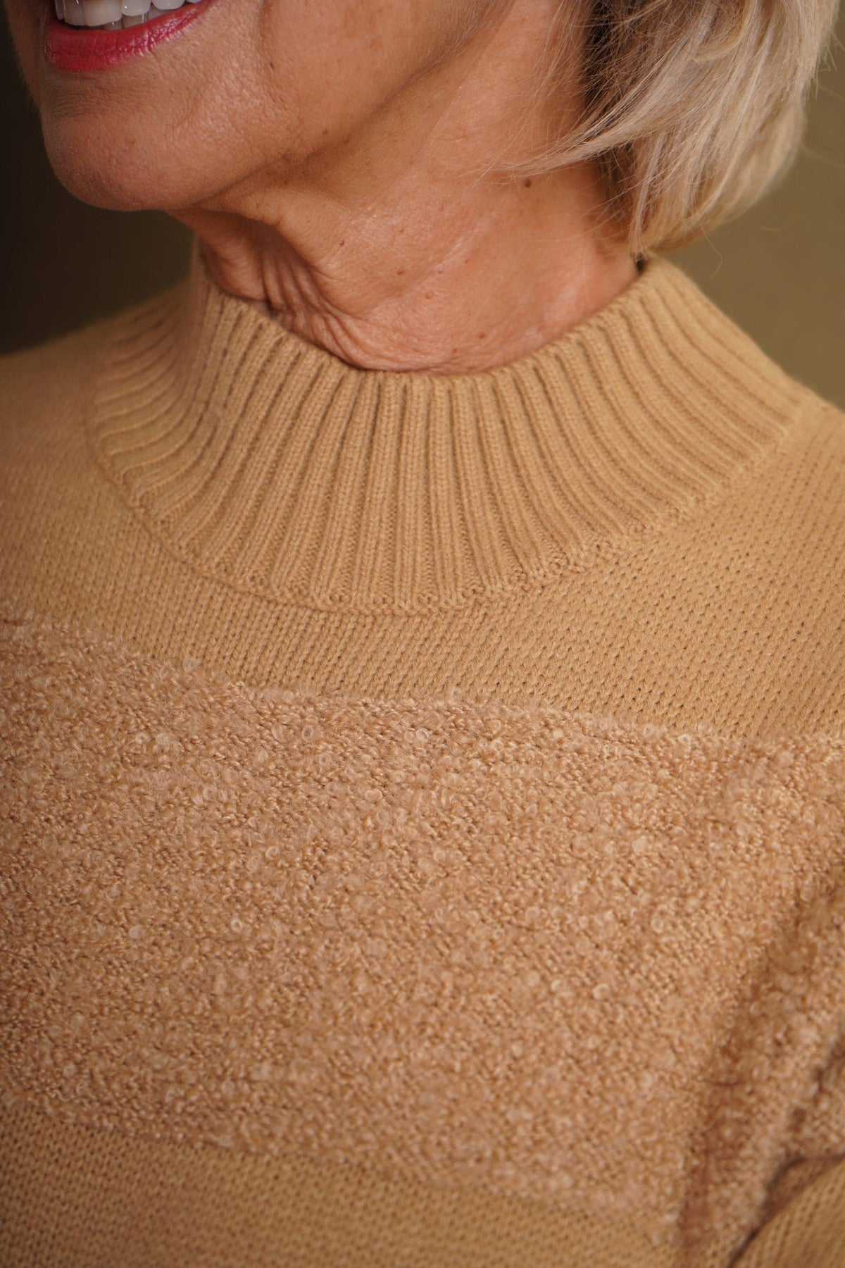 Woman sitting and smiling wearing a relaxed roll neck jumper with horizontal textured looped stripes and ribbed cuffs._3