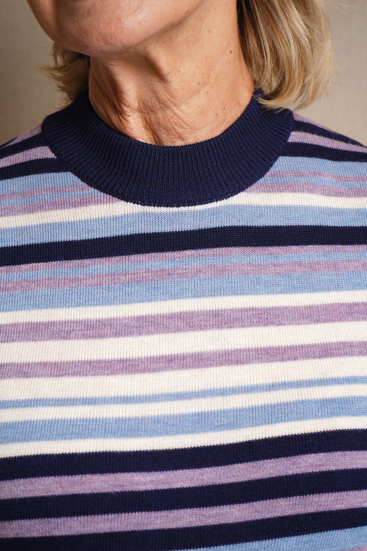 Woman wearing a long sleeve striped knit jumper with a ribbed crew neck, cuffs and hem, standing beside a wooden gate._5