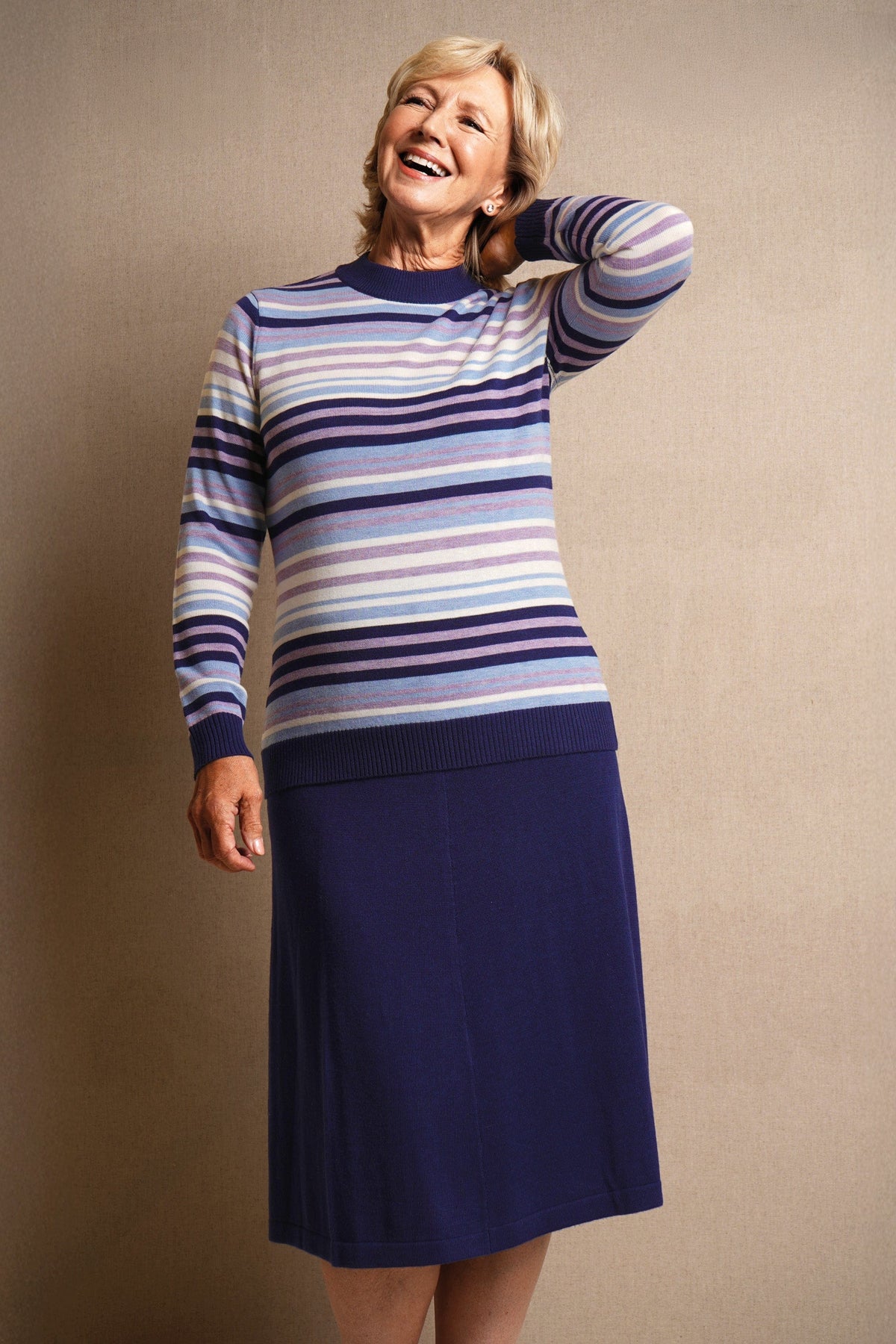 Woman wearing a long sleeve striped knit jumper with a ribbed crew neck, cuffs and hem, standing beside a wooden gate._6
