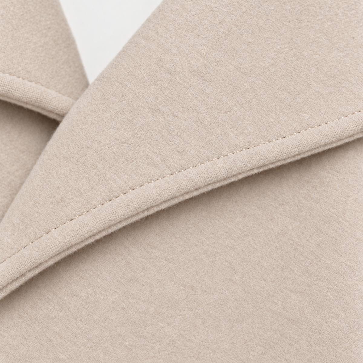 Detail view of the coat’s notched lapel and neatly stitched edge.
