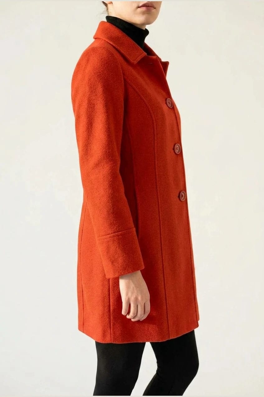 Woman wearing a knee length single breasted coat with a point collar, four front buttons, panel seams and slanted hip pockets, over trousers and ankle boots._10