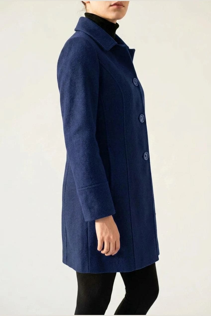 Woman wearing a knee length single breasted coat with a point collar, four front buttons, panel seams and slanted hip pockets, over trousers and ankle boots._4