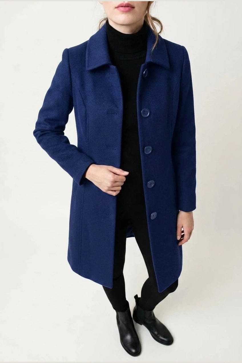 Woman wearing a knee length single breasted coat with a point collar, four front buttons, panel seams and slanted hip pockets, over trousers and ankle boots._5