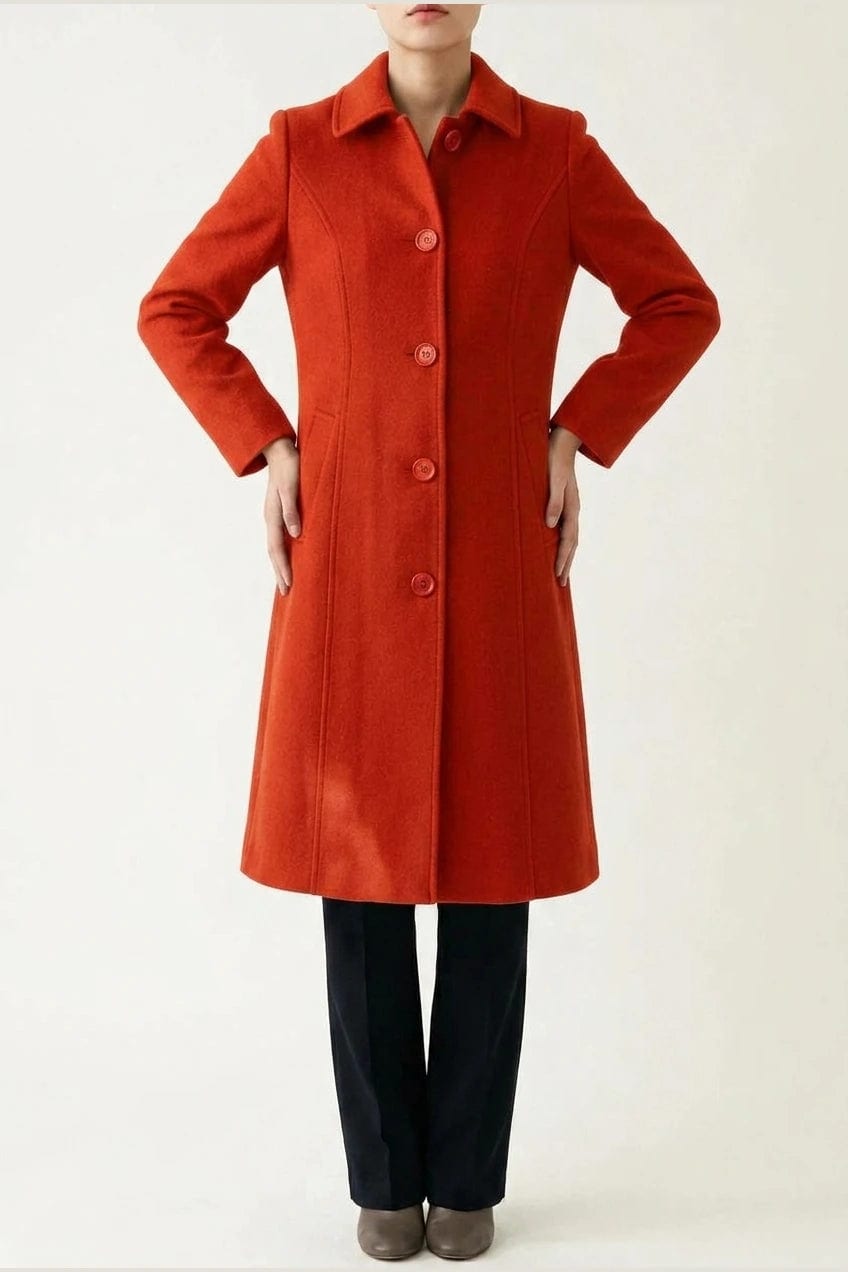 Woman wearing a knee length single breasted coat with a point collar, four front buttons, panel seams and slanted hip pockets, over trousers and ankle boots._7