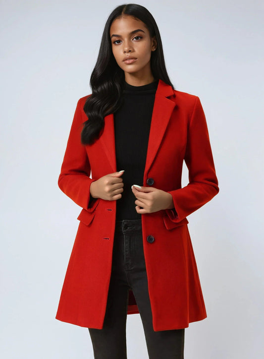 Model wearing a red tailored lapel coat over a black top and trousers, holding the button front closed.