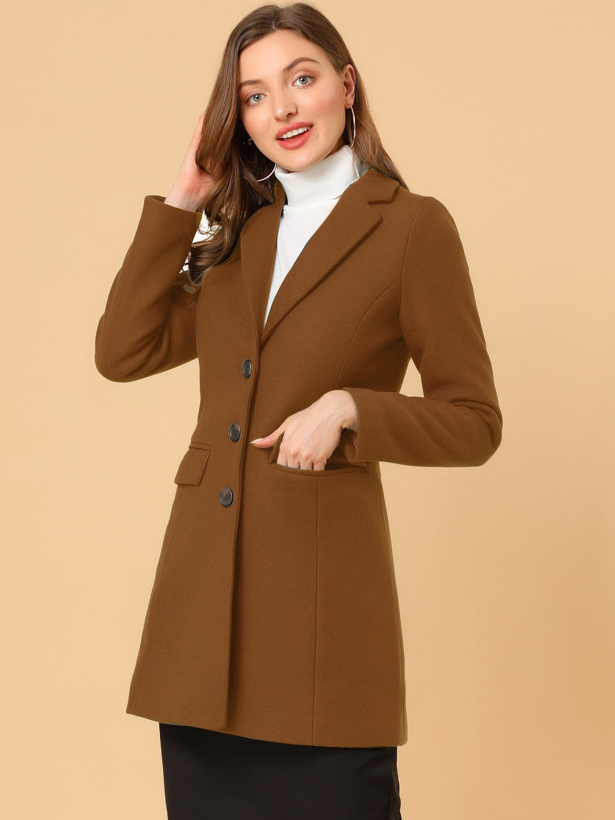 Brown lapel coat shown at an angle with one hand in a flap pocket and the other touching the hair.