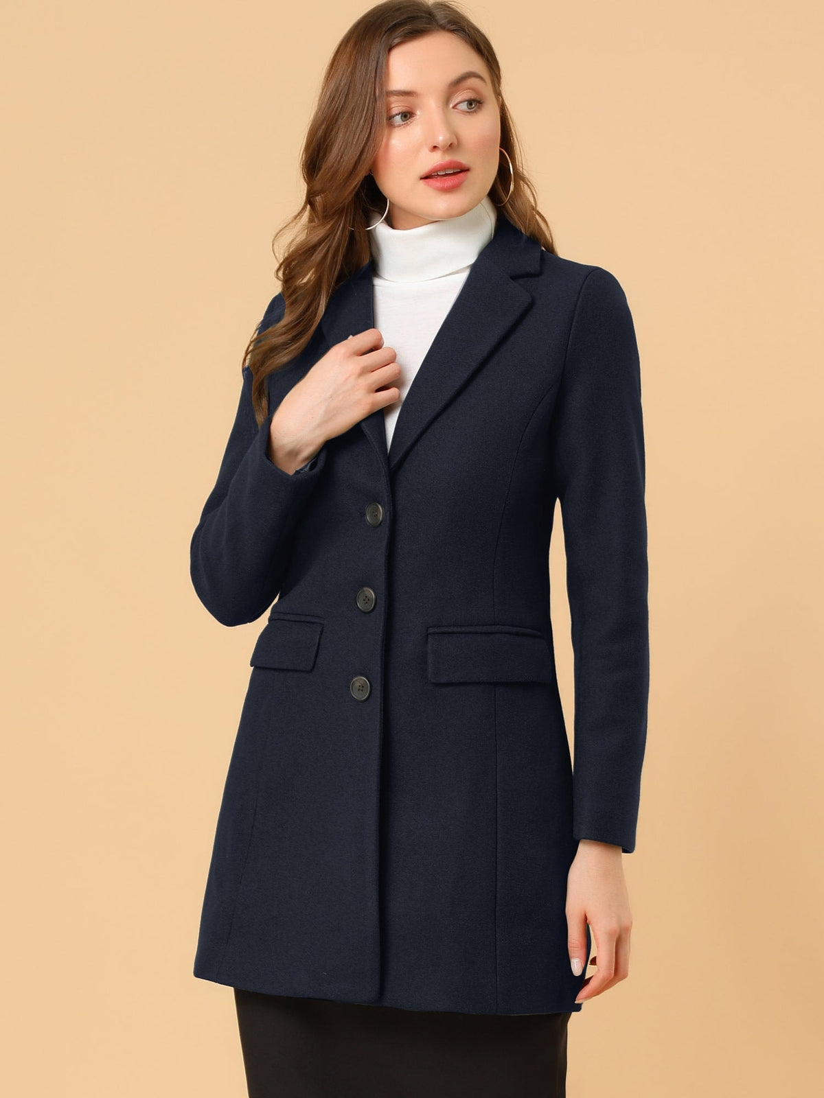 Navy tailored coat worn over a white turtleneck and black skirt, with dark buttons and flap pockets.