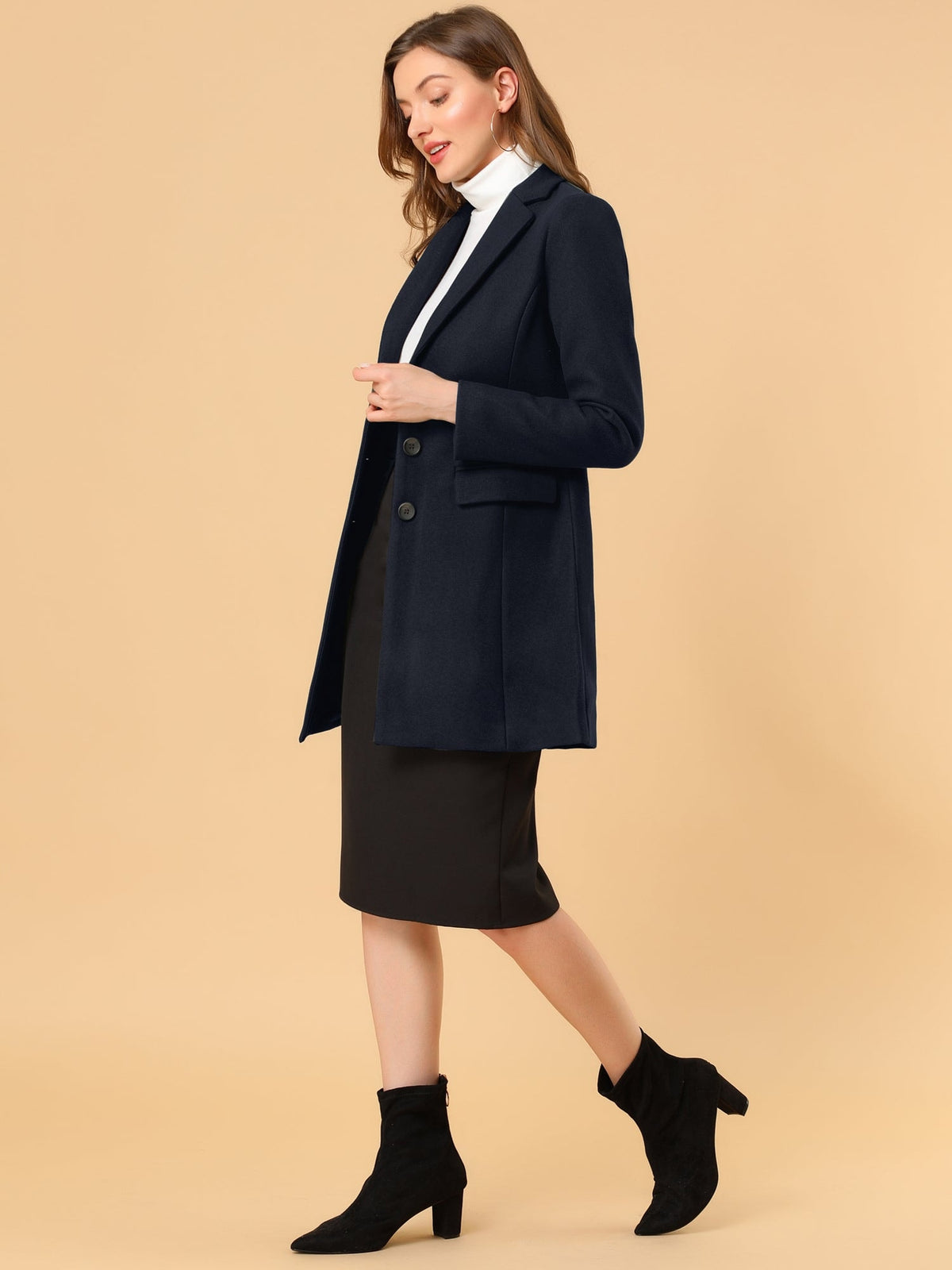 Side view of the navy lapel coat styled with a black skirt and ankle boots, showing its long tailored profile.
