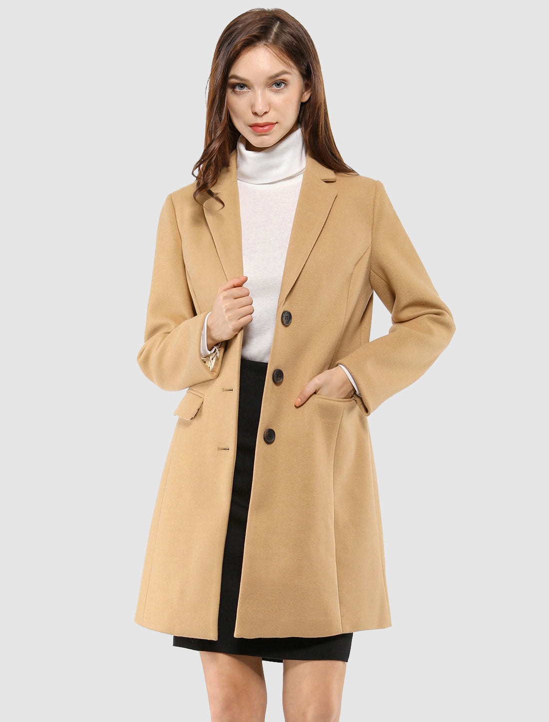 Camel tailored coat with three visible buttons and flap pockets, styled over a light turtleneck dress.