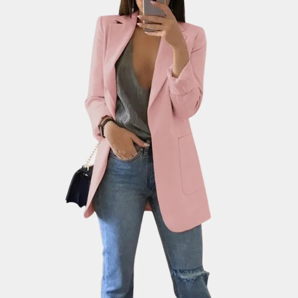 Pink longline blazer jacket with structured shoulders, notched lapels, and a front patch pocket, paired with jeans.
