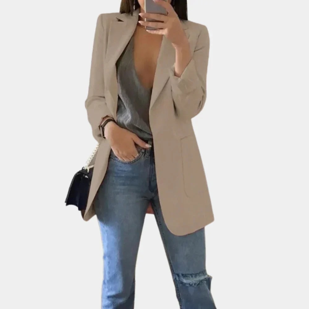 Beige tailored longline blazer jacket with notched lapels and a front pocket, layered over casual jeans.