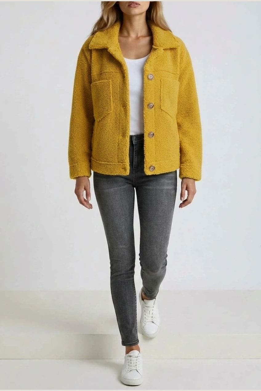 Woman wearing an open teddy-textured button-front jacket with a collar, chest pockets and lower pockets, with jeans and ankle boots._10