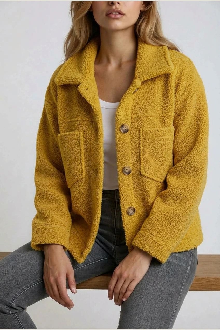 Woman wearing an open teddy-textured button-front jacket with a collar, chest pockets and lower pockets, with jeans and ankle boots._9