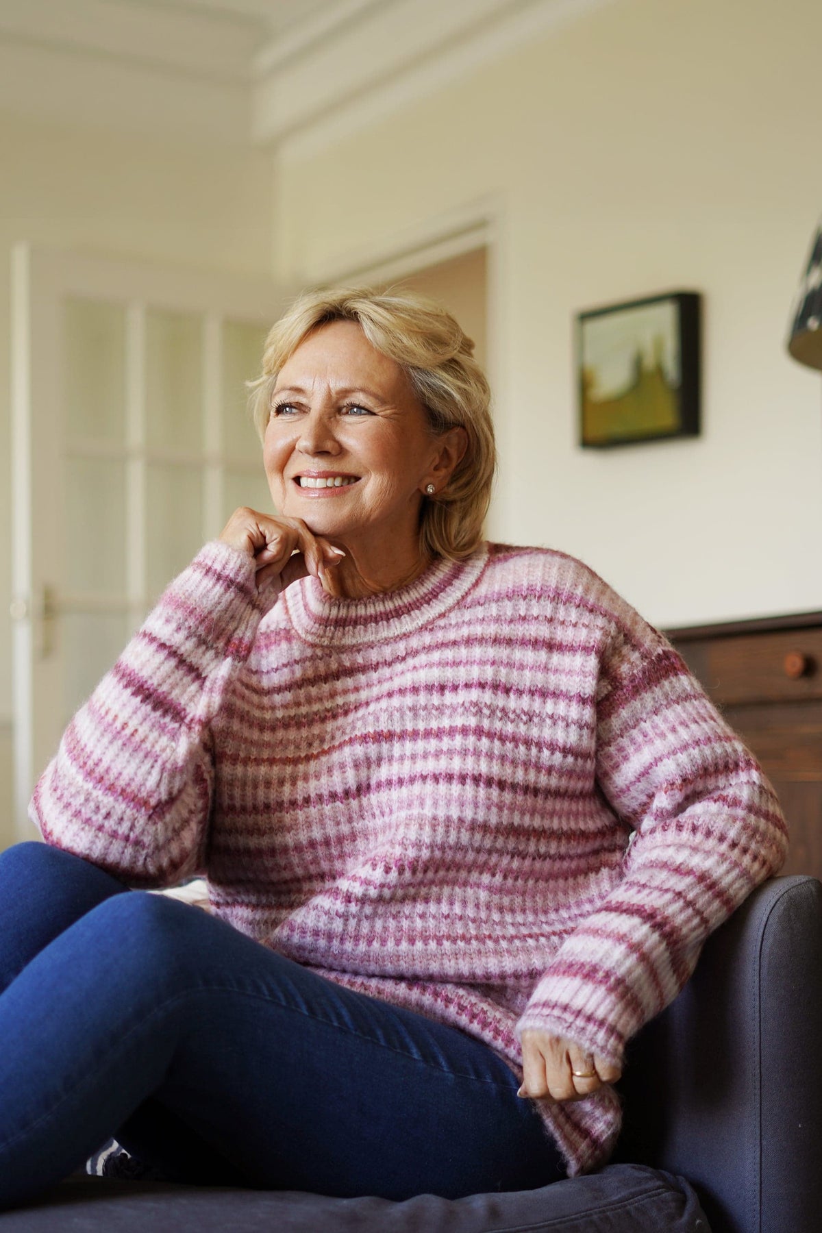 Woman sitting on a sofa wearing a striped ribbed knit crew neck jumper with long sleeves and jeans._0
