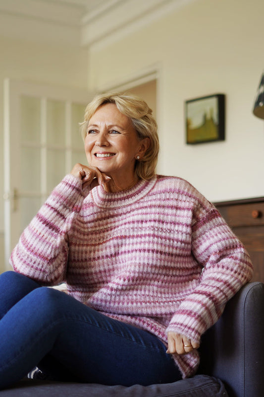 Woman sitting on a sofa wearing a striped ribbed knit crew neck jumper with long sleeves and jeans._0