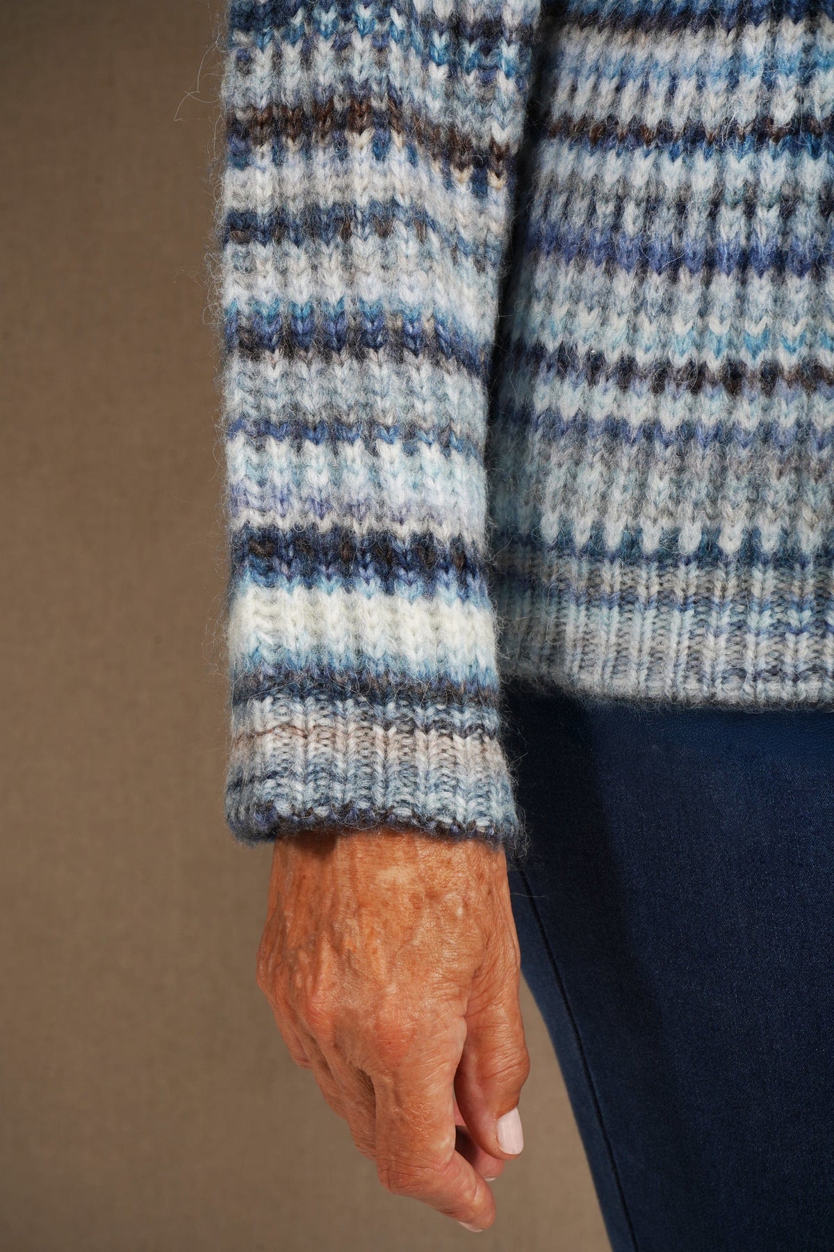 Woman sitting on a sofa wearing a striped ribbed knit crew neck jumper with long sleeves and jeans._7
