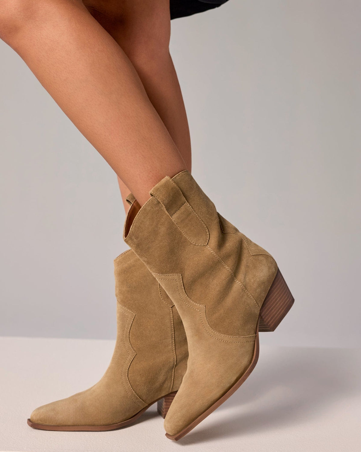 A western-inspired ankle boot with pointed toe and stacked heel in a neutral tone, displayed from a side angle._1